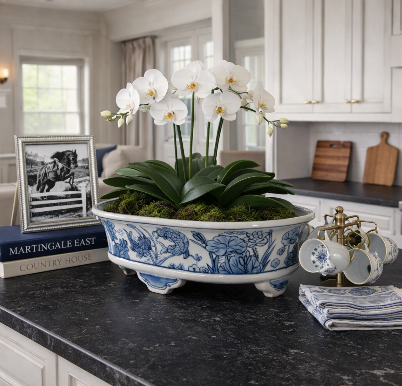 White orchids in a decorative blue and white planter on a kitchen counter.