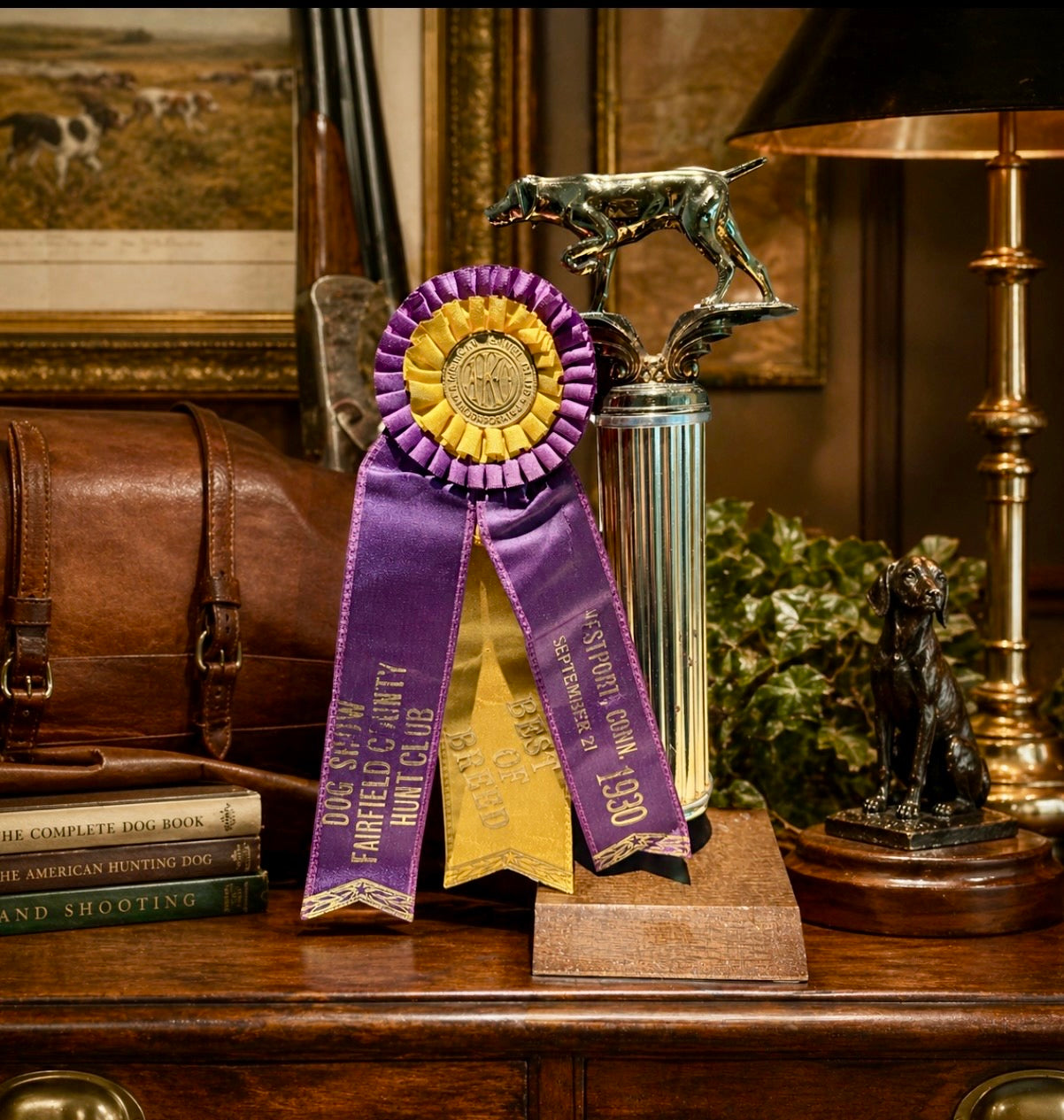 Decorative trophy with a purple ribbon on a wooden surface, surrounded by books and a lamp.