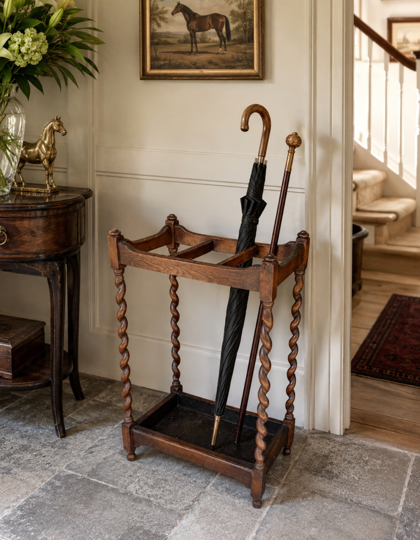Wooden umbrella stand with umbrellas in a room with a staircase and decorative elements.