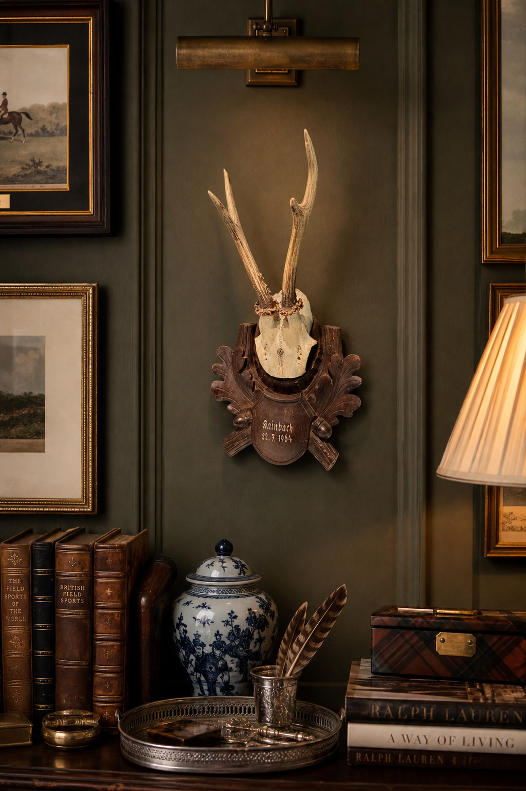 Decorative wall with mounted antlers, books, and a lamp in an interior setting.