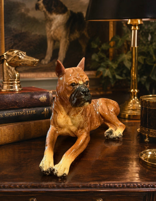 Dog figurine on a wooden surface with books and a lamp in the background