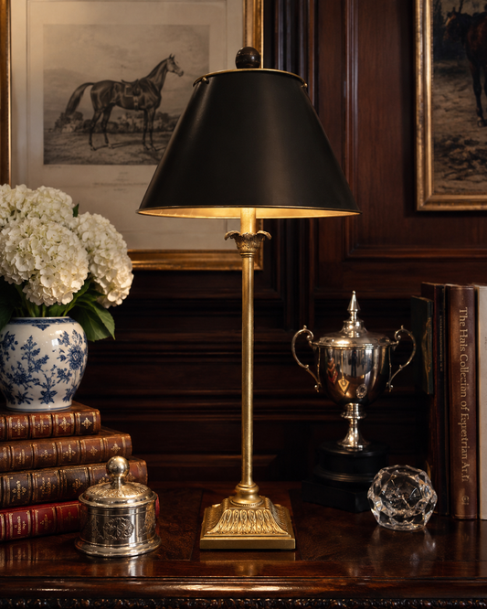 Decorative table lamp with a black shade on a wooden surface with books and decorative items.