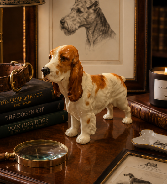 Decorative dog figurine on a wooden surface with books and a candle in the background