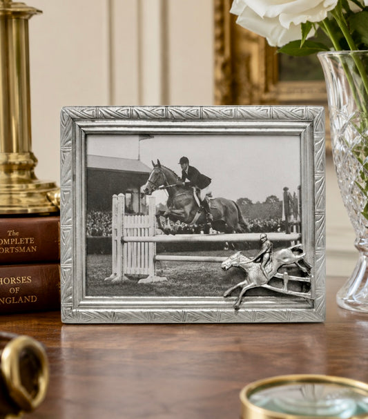 Decorative photo frame with a black and white photograph of a horse jump on a wooden surface.