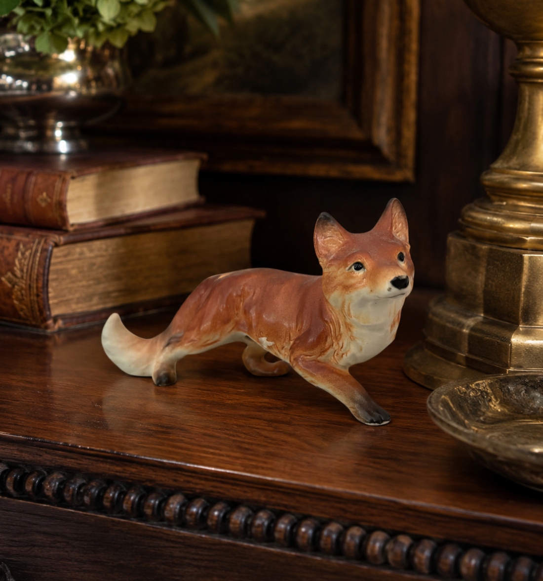 Fox figurine on a wooden surface with books and decorative items in the background