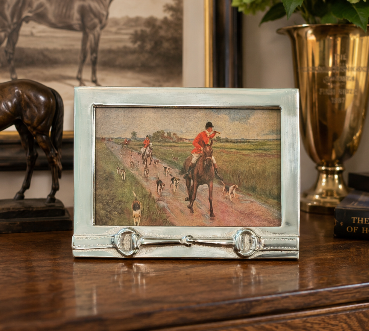 Small framed painting of a horse and rider on a path with decorative elements in the background.