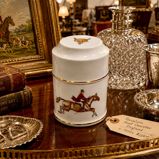 White canister with horse and rider design on a wooden table with decorative items.