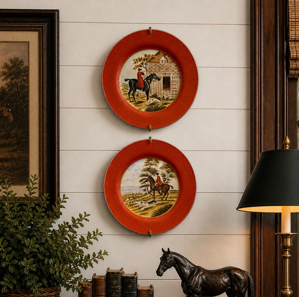 Two decorative plates with horse and cabin scenes on a wall with a lamp and plant.
