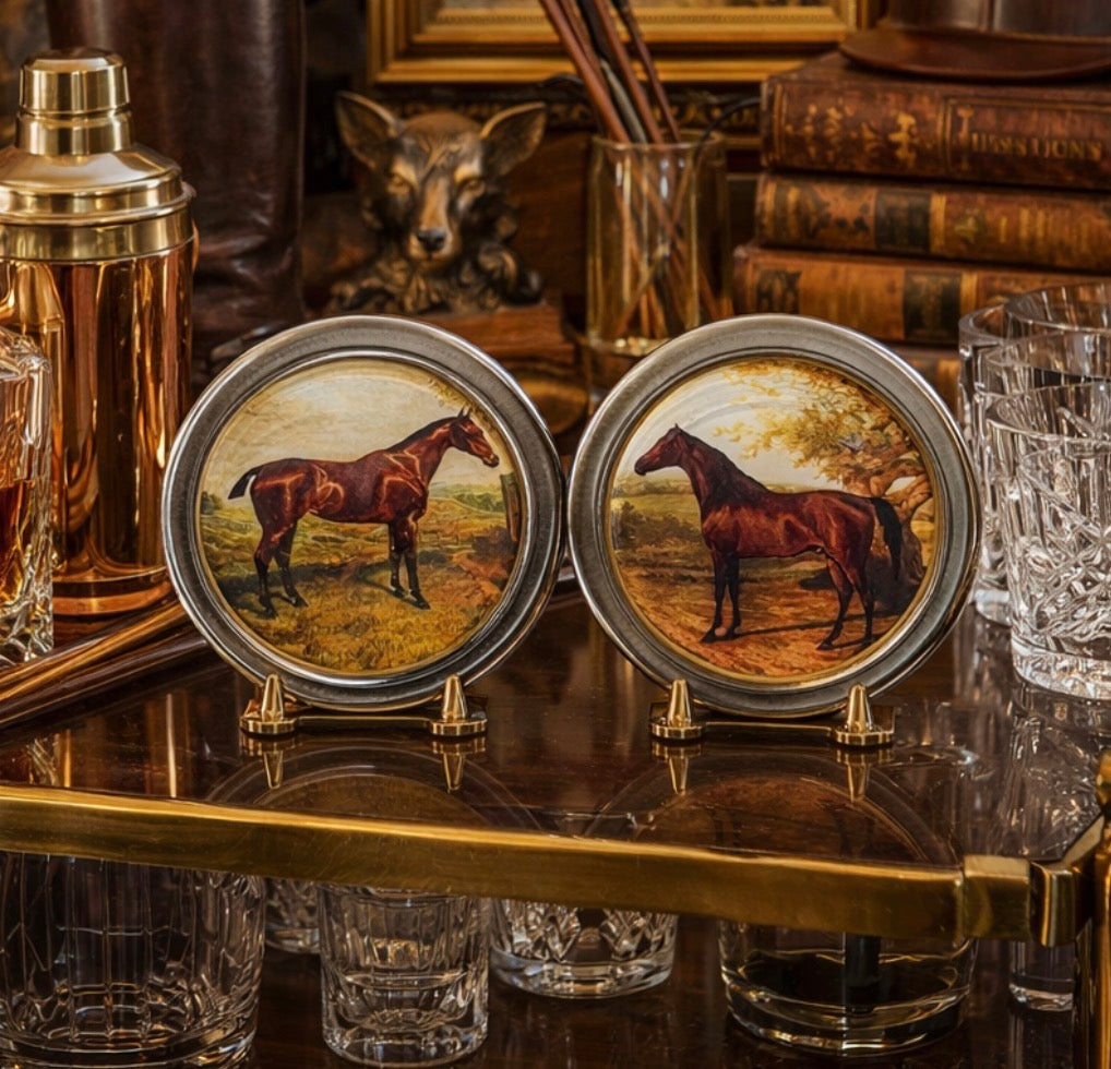 Two coasters with horse illustrations on a bar counter with glasses and decor.