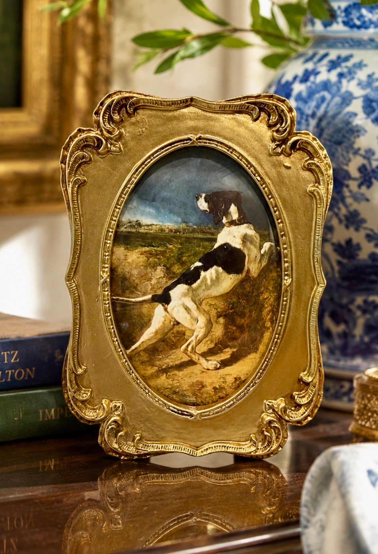 Decorative gold frame with a painting of a dog on a table