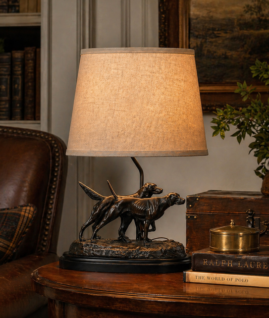 Table lamp with a bronze sculpture of two dogs on a wooden table.
