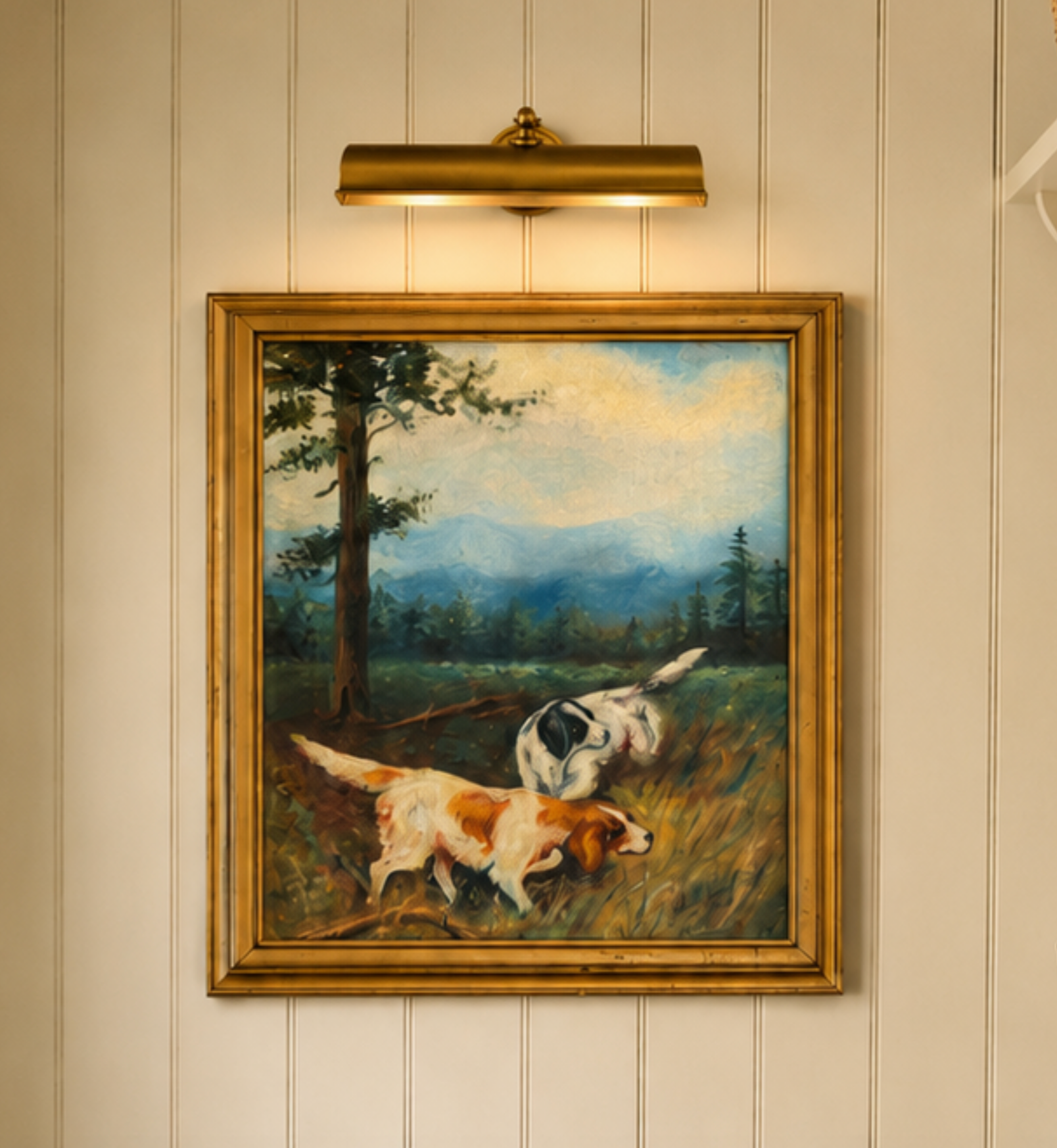 Framed painting of two dogs in a field on a wall with a light fixture above.