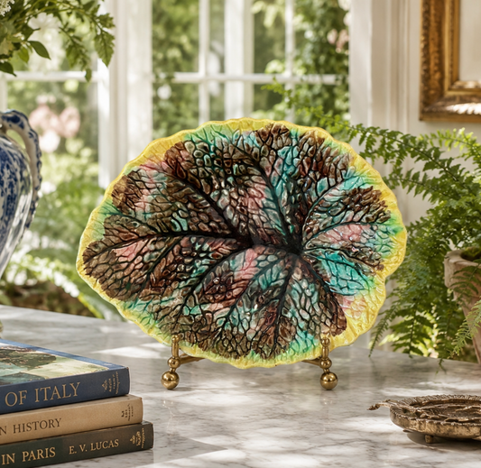 Decorative leaf-shaped object on a table with books and plants in the background