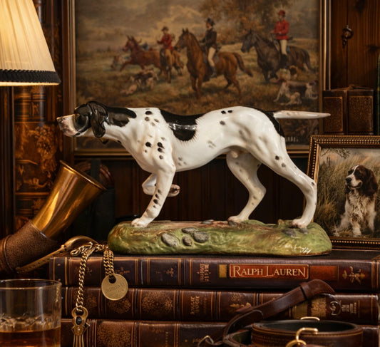 Decorative figurine of a dog on books with a painting in the background