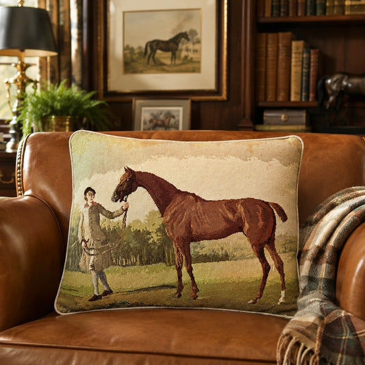 Racehorse needlepoint pillow on a brown leather chair.
