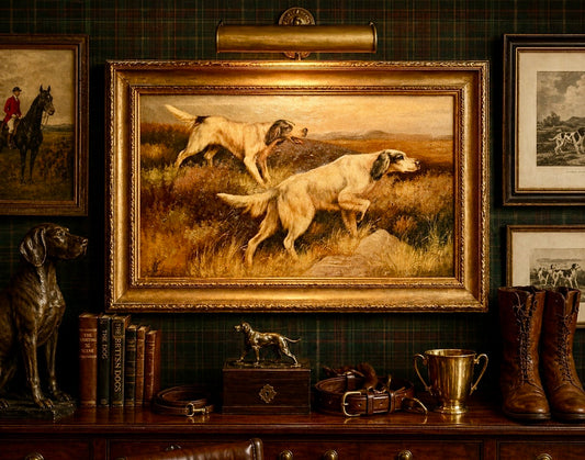 Framed painting of dogs in a field on a wall with books and decor.
