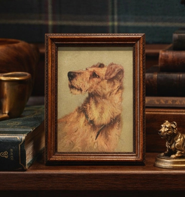 Framed portrait of a dog on a shelf with books and a small statue.