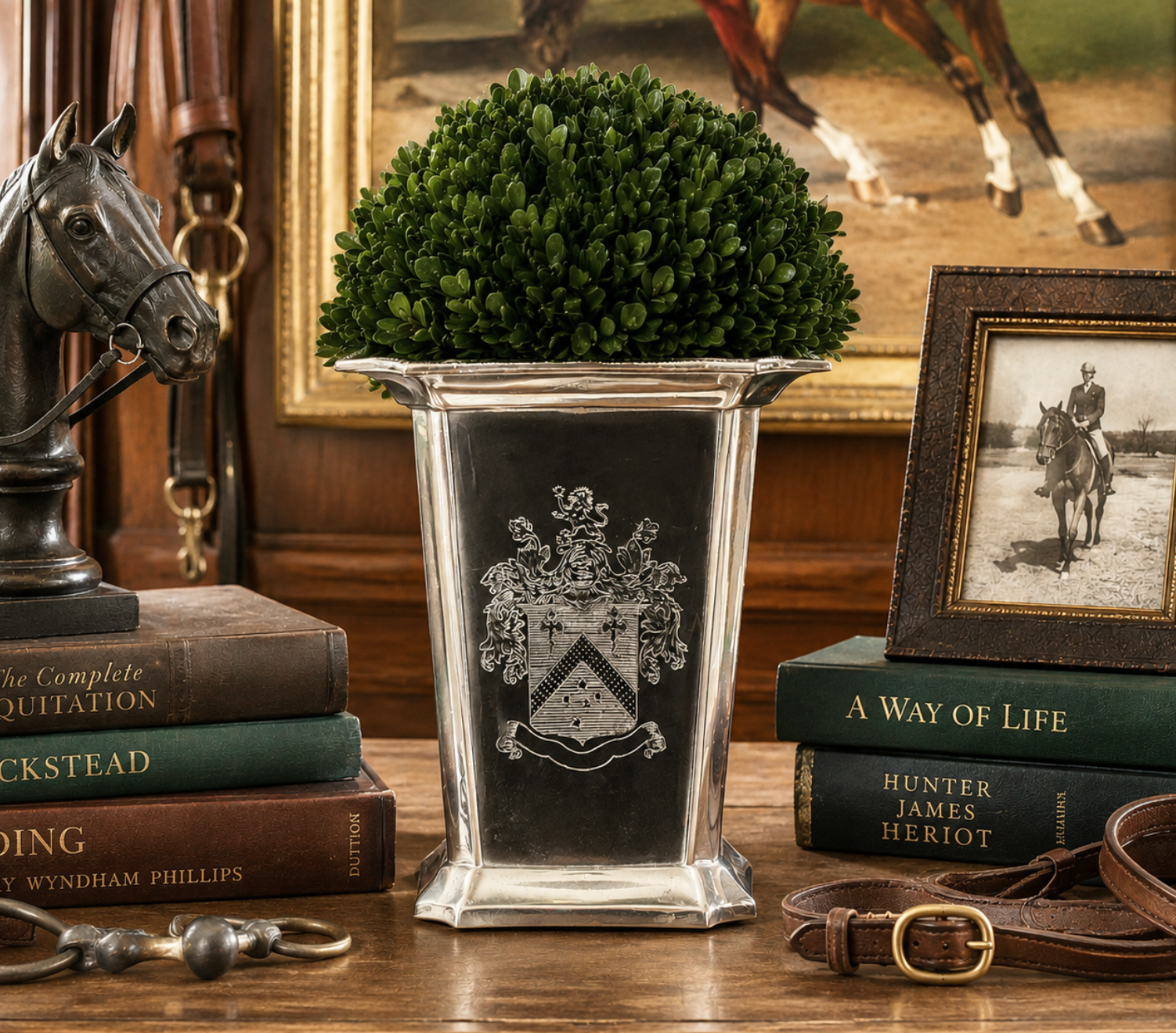 Decorative vase with a coat of arms on a wooden surface with books and horse-themed items.
